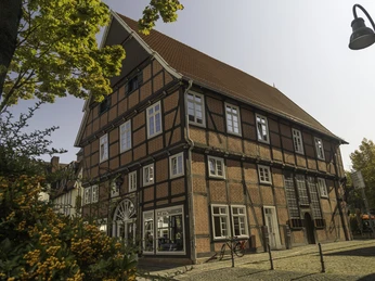Haus Ottens Ein historisches Fachwerkhaus mit roten Ziegeln und weißen Fensterrahmen, umgeben von Herbstlaub.