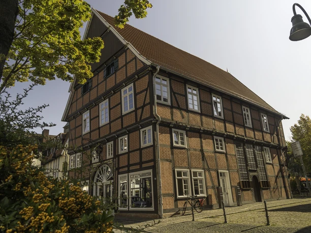 Haus Ottens Ein historisches Fachwerkhaus mit roten Ziegeln und weißen Fensterrahmen, umgeben von Herbstlaub.