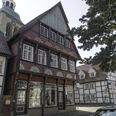 Fachwerkhaus mit roten Akzenten, großer Schaufensterfront, daneben weitere historische Fachwerkbauten.