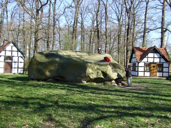 Großer Stein VII.JPG Großer Findling mit Menschen im Wald, umgeben von Fachwerkhäusern, klettern und bewundern ihn.