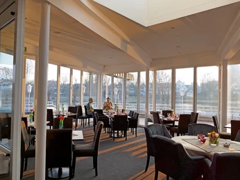 Seecafe_1.jpg Ein helles Restaurant mit großen Fenstern, modern eingerichtet, bietet eine einladende Atmosphäre.