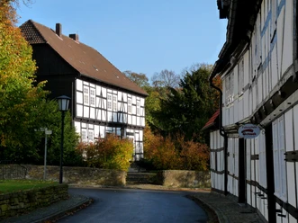 Fachwerkhäuser in Levern mit Herbstlaub, gepflasterte Straße und klare blaue Himmel im Hintergrund.