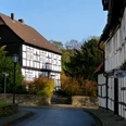 Fachwerkhäuser in Levern mit Herbstlaub, gepflasterte Straße und klare blaue Himmel im Hintergrund.