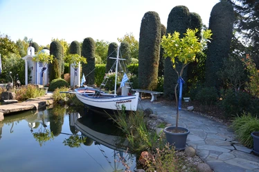rila erleben Griechenland Ein traditionelles griechisches Boot liegt an einem ruhigen Teich, umgeben von mediterraner Vegetation.