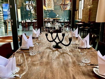 Ein elegant gedeckter Holztisch in einem stilvollen Restaurant mit rustikalen Kronleuchtern im Hintergrund.