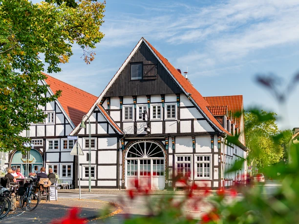 Ankervilla Wiedenbrück Fachwerkhaus mit roten Dächern und blühenden Pflanzen im Vordergrund an einem sonnigen Tag.
