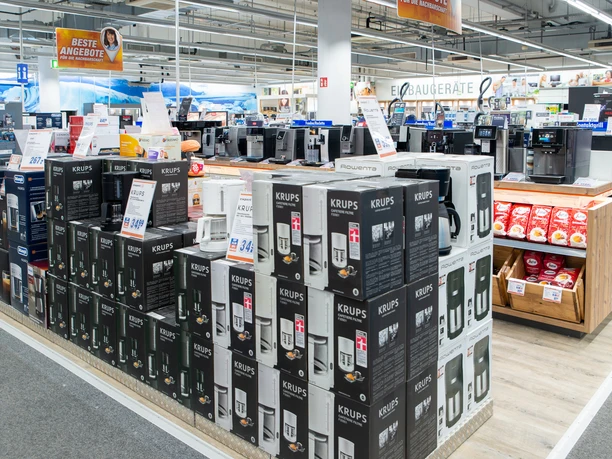 Expert-6.jpg Kartons mit Kaffeemaschinen, im Hintergrund Regale mit Kaffeevollautomaten