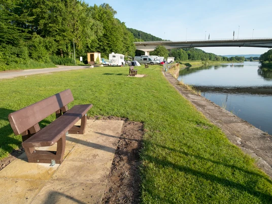Vlothoer Hafen Vlothoer Hafen, vorne eine Bank, dann eine Wiese mit Wohnmobilen. Hinten ist die Weserbrücke