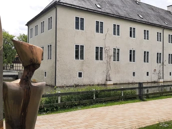 Schloss Benkhausen Schloss Benkhausen in Espelkamp, umgeben von Wassergraben und Skulptur im Vordergrund.