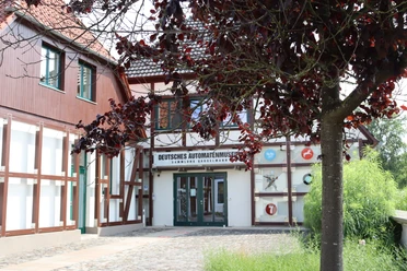 Deutsches Automatenmuseum.JPG Museumseingang mit Fachwerkfassade und überhängendem Baum, linker Bereich mit rotem Anstrich.