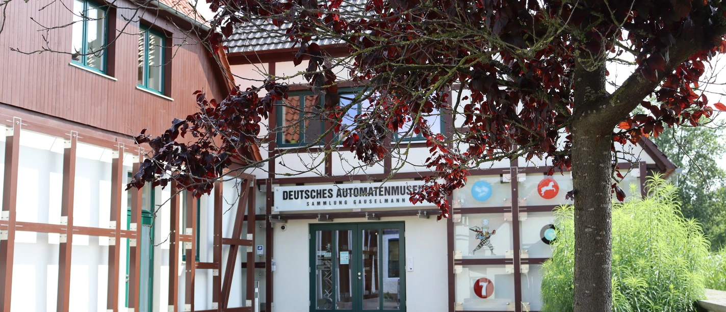 Deutsches Automatenmuseum.JPG Museumseingang mit Fachwerkfassade und überhängendem Baum, linker Bereich mit rotem Anstrich.