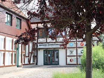 Deutsches Automatenmuseum.JPG Museumseingang mit Fachwerkfassade und überhängendem Baum, linker Bereich mit rotem Anstrich.