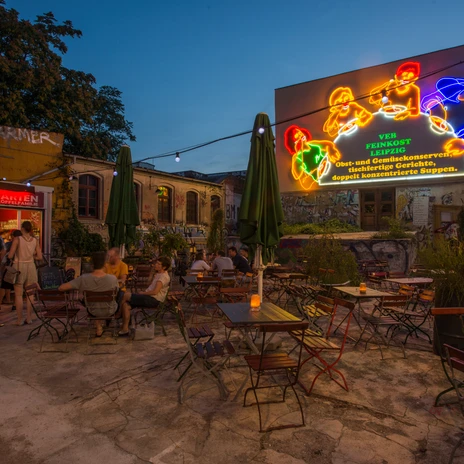 Leipzig, Sachsen, Deutschland. 30.08.2015. Szeneviertel. Die Leipziger Suedvorstadt. Biergarten unter der Loeffelfamilie. Die Loeffelfamilie leuchtet wieder. Rekonstruierte Leuchtreklame des VEB Feinkost aus DDR Zeiten in der Karl-Liebknecht-Strasse, kurz Karli genannt. Die Suedvorstadt ist ein beliebtes Wohngebiet mit Kneipen-, Kleinkunst- und Alternativszene. Engl.: Leipzig, Saxony, Germany. 30.08.2015. Beer garden. The Karl-Liebknecht-Street is the Main Street of the Leipziger Suedvorstadt The variety of restaurants, bars and cultural amenities in the Leipziger Suedvorstadt attracts locals and tourists. The Spoon Family, a former GDR luminous advertising is glowing in the dark. © copyright: Peter Hirth / Loessniger Strasse 22 / D-04275 Leipzig / Germany phone +49 3412124769 mobil +49 171 2774414 / e-mail: hirthfoto@aol.com / www.peterhirth.de / Bankverbindung: Hamburger Sparkasse / IBAN DE2320050550 / BIC HASPDEHHXXX