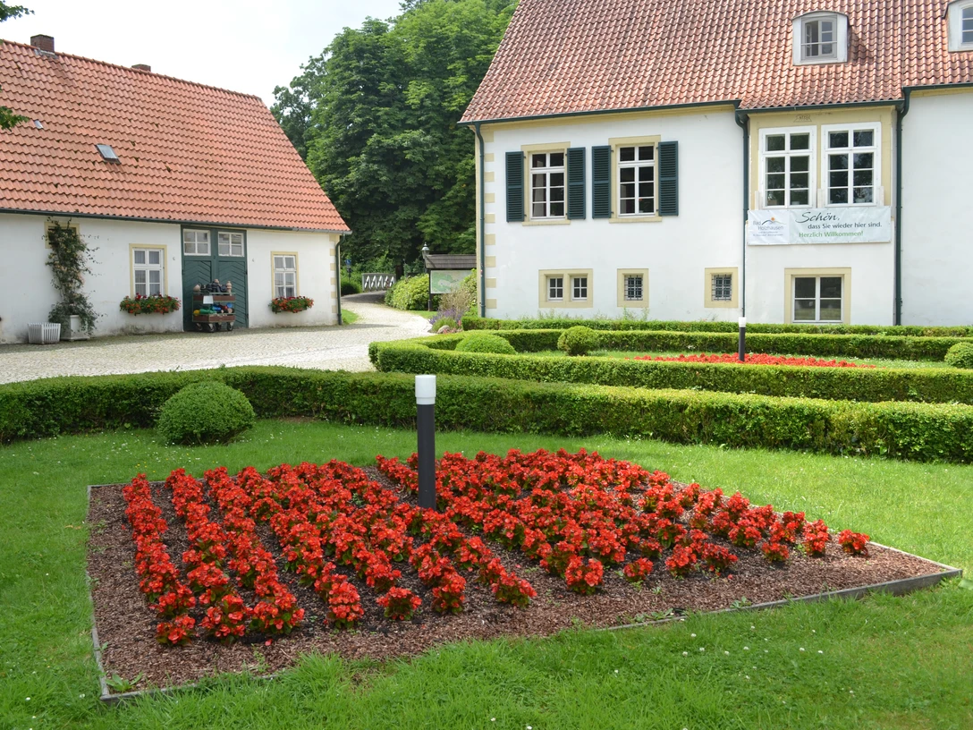 Traditionelles Gebäude im Kurpark Bad Holzhausen mit gepflegtem Gartenbereich und leuchtenden Blumen.