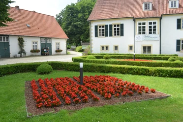 Haus des Gastes - Kurpark Bad Holzhausen Traditionelles Gebäude im Kurpark Bad Holzhausen mit gepflegtem Gartenbereich und leuchtenden Blumen.