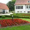 Haus des Gastes - Kurpark Bad Holzhausen Traditionelles Gebäude im Kurpark Bad Holzhausen mit gepflegtem Gartenbereich und leuchtenden Blumen.