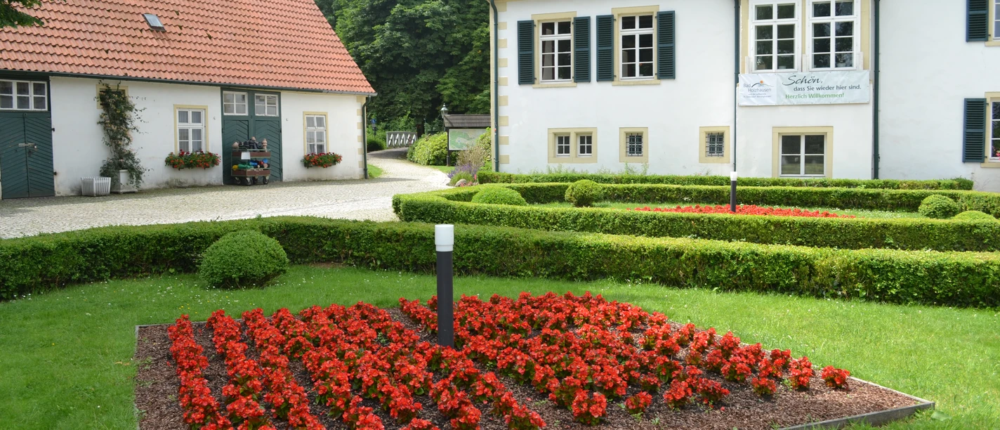 Haus des Gastes - Kurpark Bad Holzhausen Traditionelles Gebäude im Kurpark Bad Holzhausen mit gepflegtem Gartenbereich und leuchtenden Blumen.