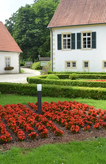 Haus des Gastes - Kurpark Bad Holzhausen Traditionelles Gebäude im Kurpark Bad Holzhausen mit gepflegtem Gartenbereich und leuchtenden Blumen.
