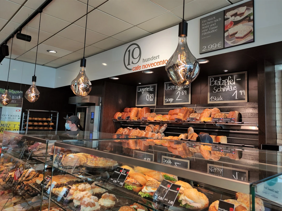 Auslage der Bäckerei, im Hintergrund Brote, vorne Gebäck. Retro Lampen stechen hervor