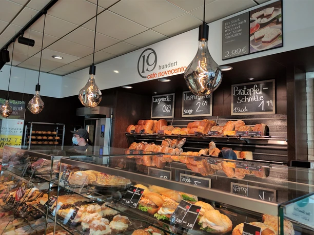 Auslage der Bäckerei, im Hintergrund Brote, vorne Gebäck. Retro Lampen stechen hervor