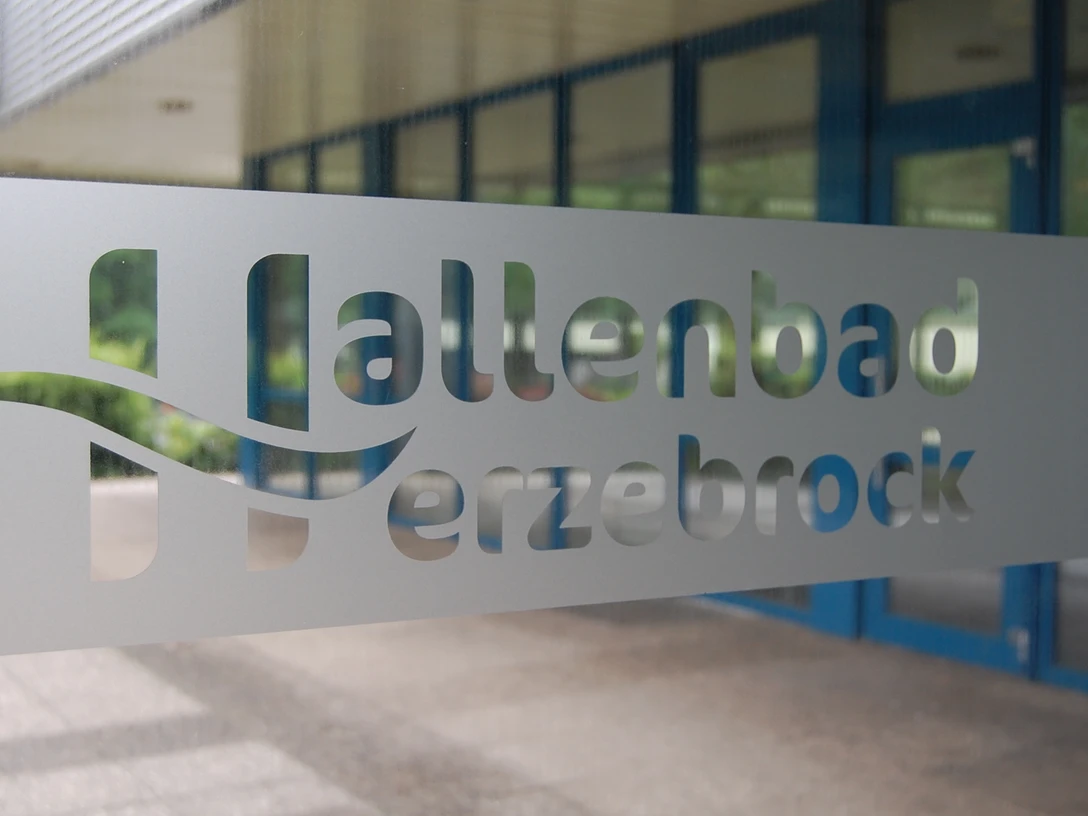 Hallenbad Herzebrock Schriftzug.JPG Eingangstür mit dem ausgeschriebenen Schriftzug "Hallenbad Herzebrock" aus mattiertem Glas.