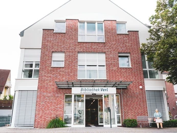 Eingang der Stadtbibliothek Verl, modernes Gebäude mit roter Ziegelfassade und großen Fenstern.