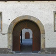 Rundbogen-Eingang aus Holz und Stein am Michaelskloster mit zwei bunten Fenstern links und rechts.