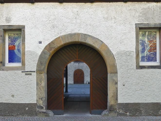Eingang Michaelskloster Rundbogen-Eingang aus Holz und Stein am Michaelskloster mit zwei bunten Fenstern links und rechts.
