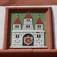 0W1A0206.jpg Wappenrelief mit drei Türmen und rotem Schild in einem Ziegelrahmen an einer weiß verputzten Wand.