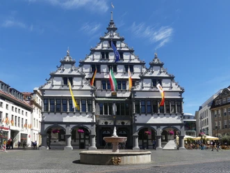 Historisches Rathaus von Paderborn mit markanter Stufenfassade und bunten Fahnen geschmückt.