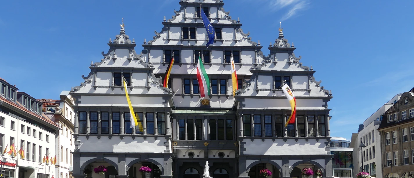 Historisches Rathaus von Paderborn mit markanter Stufenfassade und bunten Fahnen geschmückt.