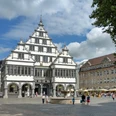 Historisches Rathaus in Paderborn mit markantem Giebel, umgeben von Besuchern auf dem belebten Platz.