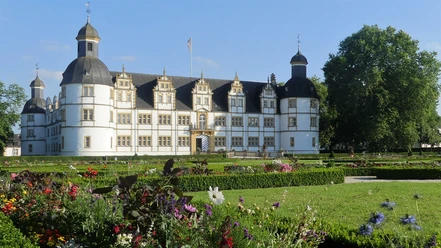 Schloß Neuhaus Historisches Schloss Neuhaus in Paderborn umgeben von gepflegtem Park, blühenden Blumenbeeten und Bäumen.