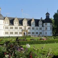 Schloß Neuhaus Historisches Schloss Neuhaus in Paderborn umgeben von gepflegtem Park, blühenden Blumenbeeten und Bäumen.