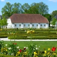 Städtische Galerie in der Reithalle Historisches Gebäude hinter symmetrischen Gartenanlagen mit bunten Blumen und gepflegten Wegen.