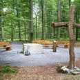 Friedwald Nonnebusch, Andachtsplatz Andachtsplatz im Friedwald Nonnebusch mit Holzbänken, einem großen Kreuz und umgeben von Bäumen.