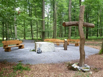 Friedwald Nonnebusch, Andachtsplatz Andachtsplatz im Friedwald Nonnebusch mit Holzbänken, einem großen Kreuz und umgeben von Bäumen.