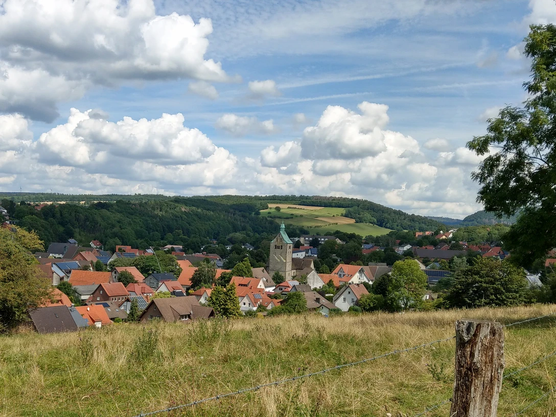 Blick auf Neuenbeken Neuenbeken mit seiner zentralen Kirche im Vordergrund, umgeben von Wiesen und bewaldeten Hügeln.