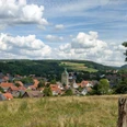 Blick auf Neuenbeken Neuenbeken mit seiner zentralen Kirche im Vordergrund, umgeben von Wiesen und bewaldeten Hügeln.