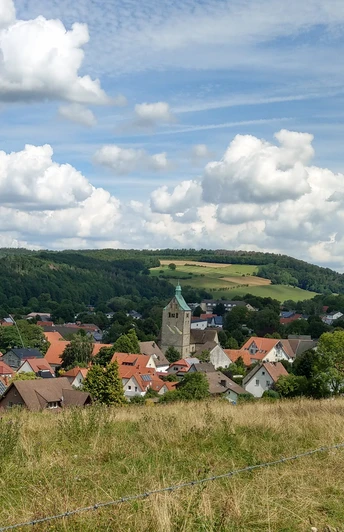 Blick auf Neuenbeken Neuenbeken mit seiner zentralen Kirche im Vordergrund, umgeben von Wiesen und bewaldeten Hügeln.