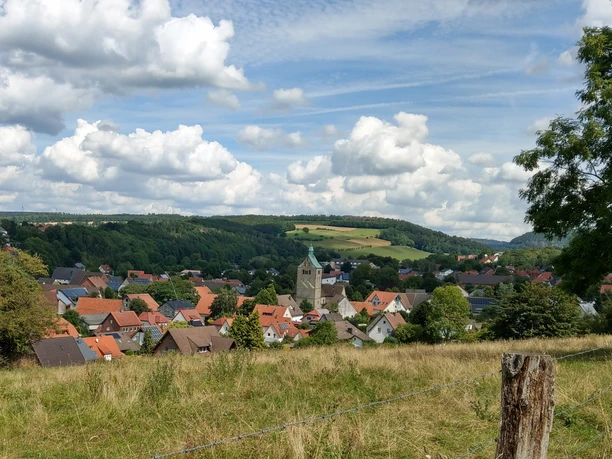 Blick auf Neuenbeken Neuenbeken mit seiner zentralen Kirche im Vordergrund, umgeben von Wiesen und bewaldeten Hügeln.