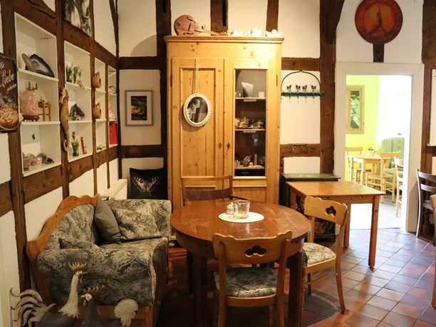 Gemütlicher Innenraum eines Cafés mit Holzmöbeln, gemütlichen Kissen, rustikalen Details und Deko.