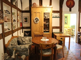 Café Waldkristall.jpg Gemütlicher Innenraum eines Cafés mit Holzmöbeln, gemütlichen Kissen, rustikalen Details und Deko.