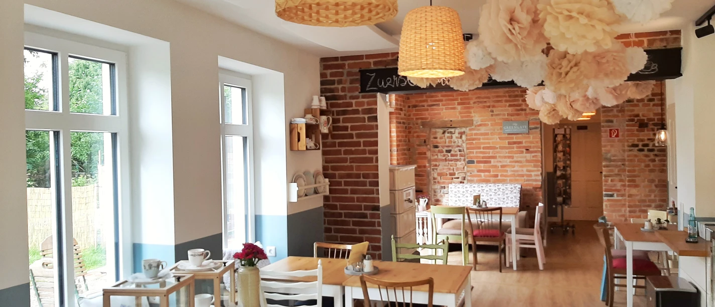 Kaffeeküche in Hille Helle Kaffeeküche mit Holzfußboden, gemusterten Hängelampen, dekorativen Blumen und Holzstühlen.