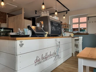 Kaffeeküche in Hille Die Kaffeeküche in Hille mit modernen Lampen, einem großen Tresen und hellen Sitzgelegenheiten.