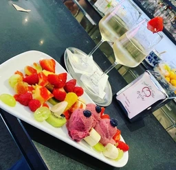 Eiscafé Pacini_Luebbecke.jpg Frisches Obst und drei Kugeln Fruchteis mit Gläsern Weißwein auf einem Tisch im Eiscafé.