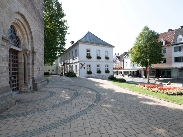 Kirchplatz und Fußgängerzone in Steinheim Pflastersteine vor der Kirche, mit Blumenbeet und historischen Gebäuden im Hintergrund.