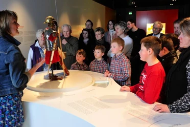 Kalkriese ... total Führung im Museum Kalkriese mit Kindern und Erwachsenen vor einer römischen Rüstung.