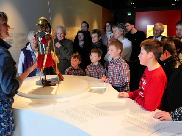 Kalkriese ... total Führung im Museum Kalkriese mit Kindern und Erwachsenen vor einer römischen Rüstung.