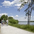 Radler am Lippesee Radfahrer auf einem sonnigen Weg am Lippesee, flache Vegetation und blauer Himmel im Hintergrund.